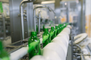 water-factory-water-bottling-line-processing-bottling-pure-mineral-water-into-small-green-glass-bottles-selective-focus